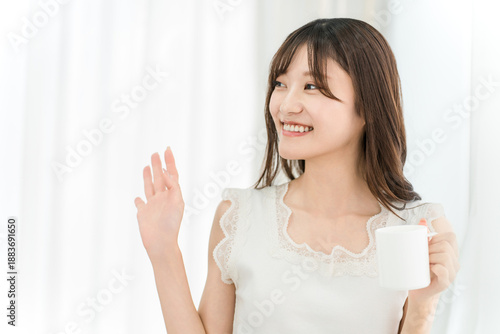 Wallpaper Mural Smiling Asian woman drinking hot water, coffee, or a hot drink at home in the morning (Good morning, waving) Torontodigital.ca