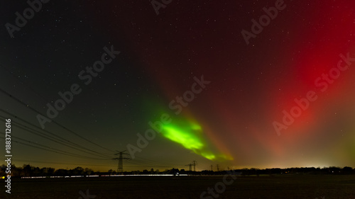 A spectacular view of the Aurora Borealis (Northern Lights) illuminating the night sky near Hamburg, Germany. 
The long-exposure photograph captures intense shades of green and rare red pillars stretc