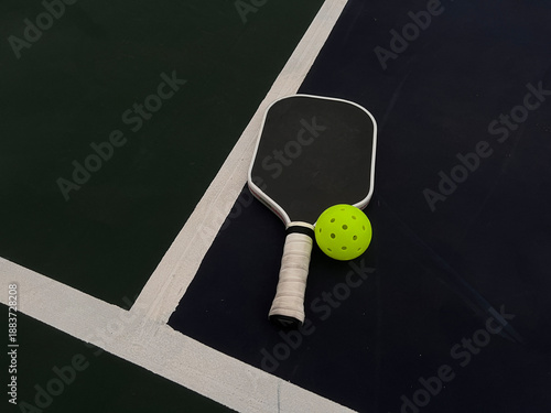 Pickleball paddle and ball in the blue and green court ground