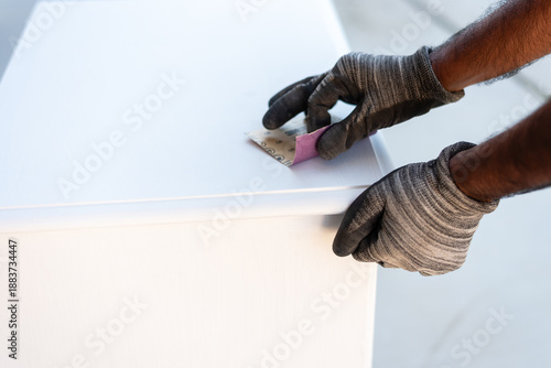 Cuadro en lienzo Worker sanding white cabinet outdoors with safety gear