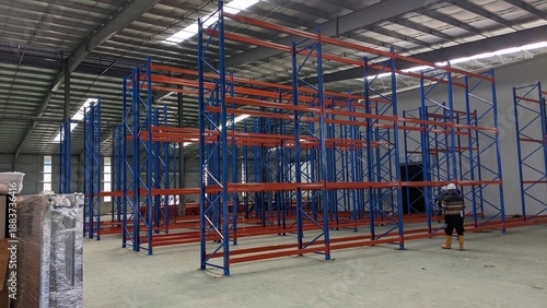 Принти на полотні Empty Industrial Warehouse Interior with Blue and Orange Metal Pallet Racking Sy