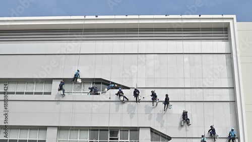 A team of professionals performs exterior maintenance on a tall building, showcasing the importance of safety and teamwork in high-rise construction environments.