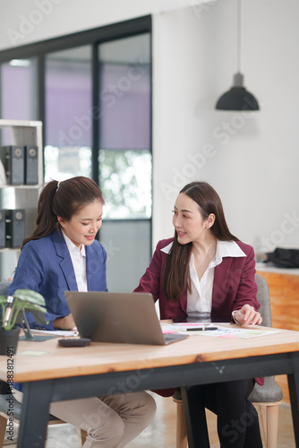 Фотография Asian businesswoman sitting at work using laptop talking and consulting in offic