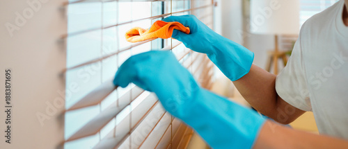 Canvas-taulu young man worker wear blue glove , cleaning interior work in house, holding wipe, rag cloth dust to clean window blinds
