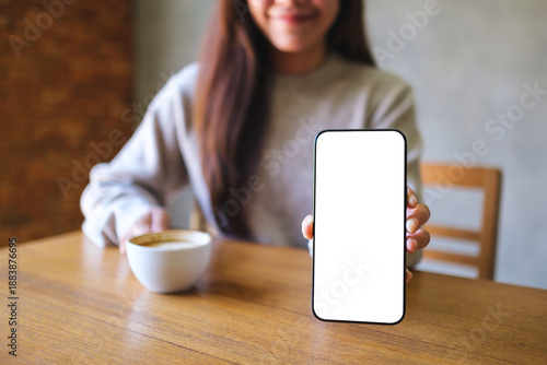 Wallpaper Mural Mockup image of a woman holding and showing a mobile phone with blank white screen while drinking cafe Torontodigital.ca