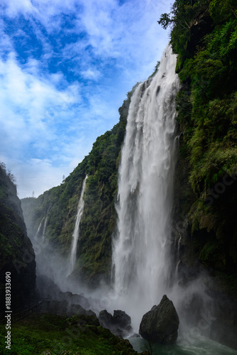 Multiple waterfalls cascade into the deep Malinghe Canyon, where a lush emerald river carves through layered rock formations in Guizhou's karst landscape.