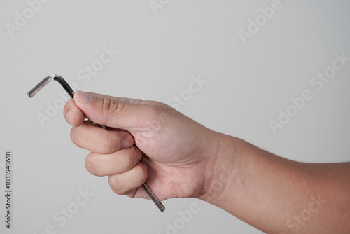 Schilderij op canvas Male person hand holding hexagonal allen L key wrench, over grey