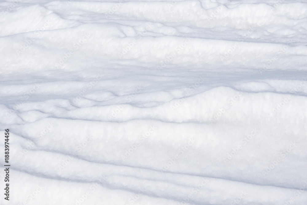 Fototapeta premium Textured white snow surface with gentle undulations and soft shadows, creating a serene winter landscape, suitable for backgrounds, seasonal themes, or nature-related projects