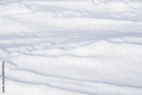 Textured white snow surface with gentle undulations and soft shadows, creating a serene winter landscape, suitable for backgrounds, seasonal themes, or nature-related projects