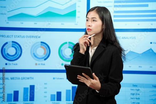 Canvastavla Asian businesswoman analyzing reports before digital dashboards evaluating impor