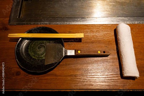 Traditional Okonomiyaki Table Setting with Chopsticks and Metal Spatula in Osaka Restaurant