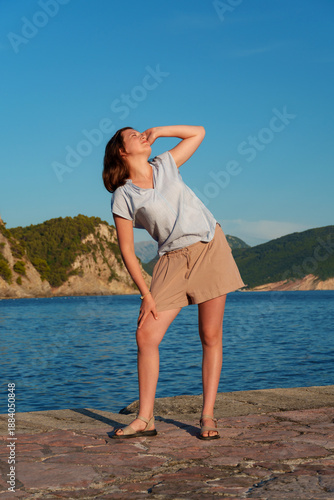 Schilderij op canvas Artistic portrait of woman leaning back enjoying sun in Petrovac Montenegro, full length, emotional pose, summer light, Mediterranean sea