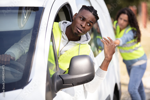 strong young woman pushing a car while man emboldens her