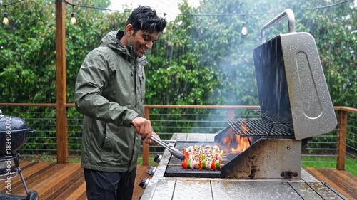 Man Grilling Colorful Vegetable Skewers on a Grill in the Rain