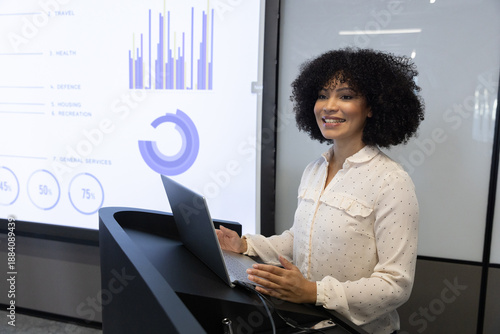 Tablou pe pânză Female presenter in blouse presenting bar, circular charts on laptop at office p