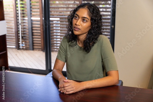 Asian indian woman in top sitting at desk clasping hands by sliding doors overlooking deck Free Download Asian indian woman in top sitting at desk clasping hands by sliding doors overlooking deck - GFXLoad
