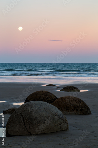 Moeraki boulders and moon at dusk on beach