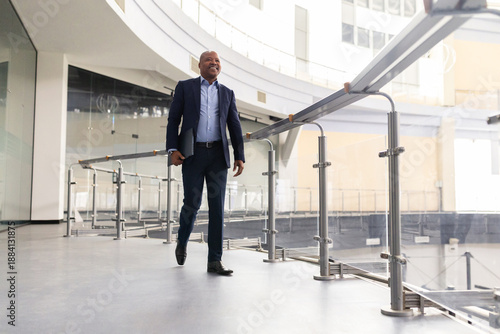 Foto Confident black mature businessman walking with tablet in hand inside modern off