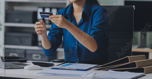 Billede på lærred Young businesswoman is holding two credit cards with a worried expression, tryin