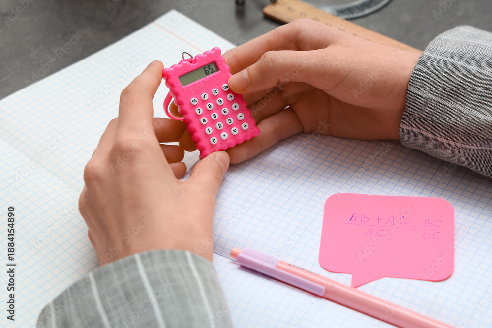 Naklejka premium Female hands with calculator, copybooks and math formula on table, closeup