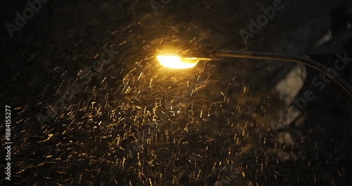 Street light illuminating falling snow during snowstorm at night. Above, close up, telephoto view, real time video, dark background, no people