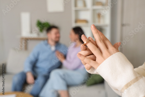Fotografie Young woman taking off wedding ring and her husband with mistress at home, closeup