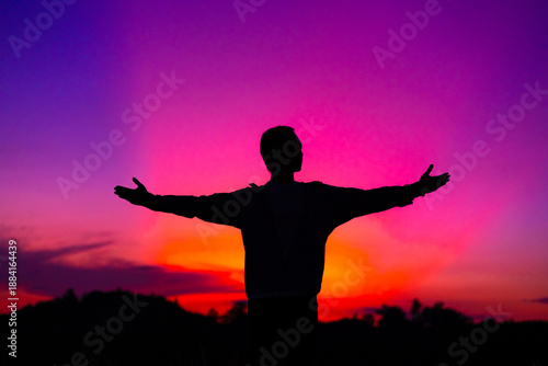 Silhouette of a man with hands raised in the sunset concept for religion, worship, prayer and praise