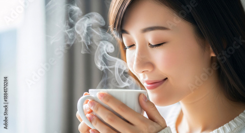 Serene Asian woman enjoying a steaming cup of coffee, conveying warmth, comfort, and relaxation
