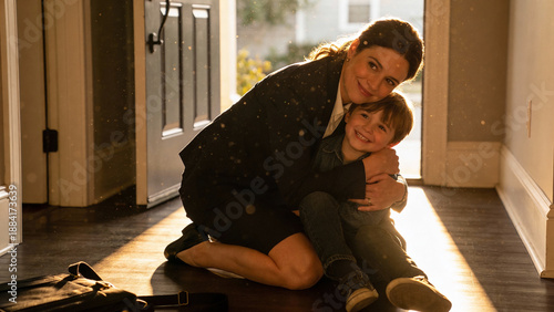 A mother hugs her child in front of the house while kneeling.