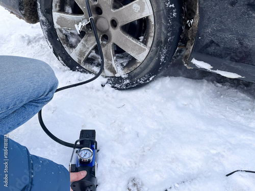 Inflating car tires. Electric pump. Winter. Day.
