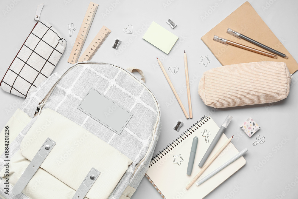 Naklejka premium Stylish school backpack with different stationery supplies on grey background