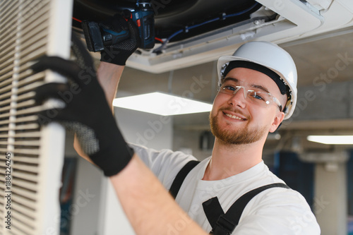 Φωτογραφία Technician repairing ceiling air conditioning unit with drill