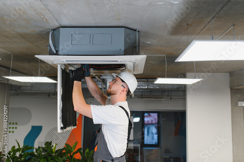 Hvac technician repairing ceiling air conditioning system