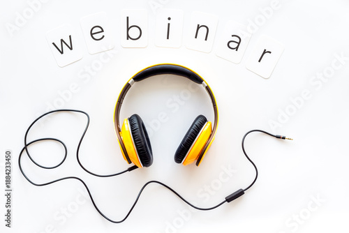 Webinar word on paper cards. Headphones on white table workspace, top view.