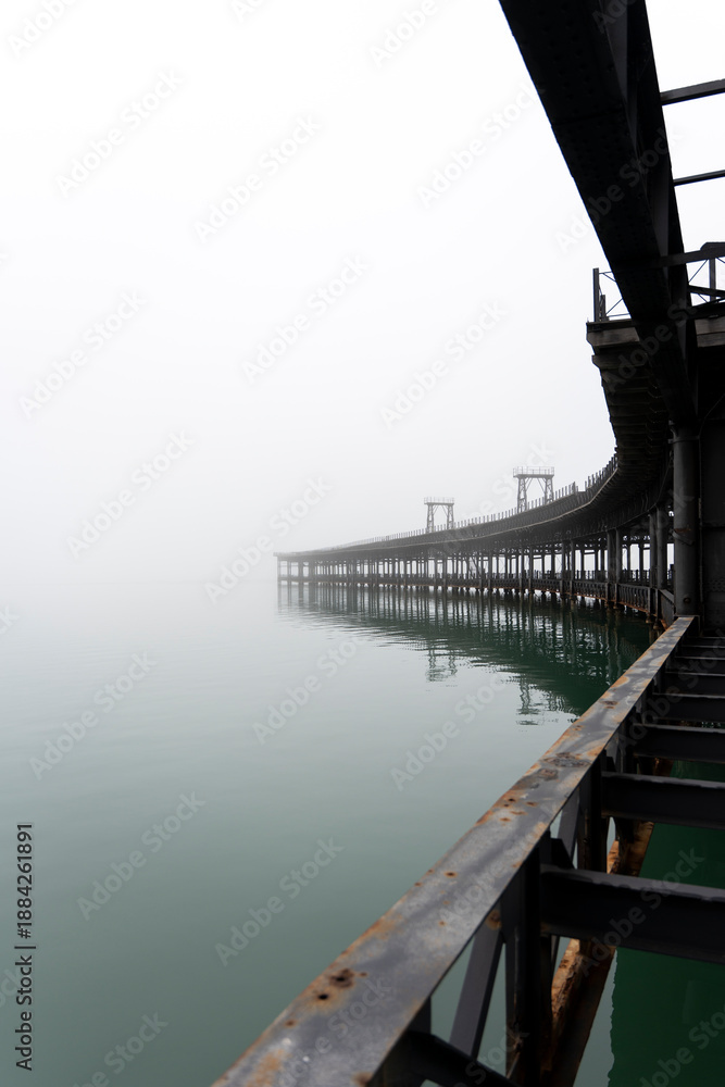 Fototapeta premium Tinto River dock under the fog. Huelva. Vertical composition
