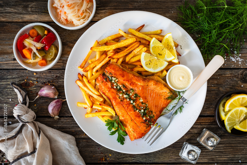Fototapeta premium Fried salmon fillet with frites and mayonnaise on wooden table. Top view