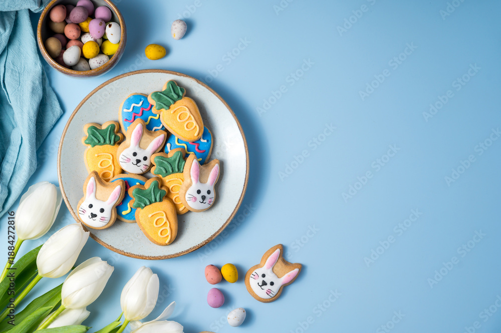 Fototapeta premium Easter spring holiday background with easter cookies in a plate: bunny, carrot and egg with white tulips