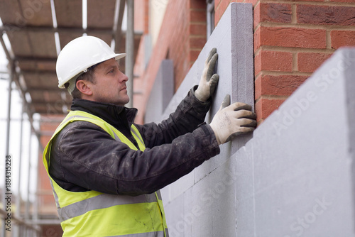 Construction worker installing insulation panels on residential building facade
