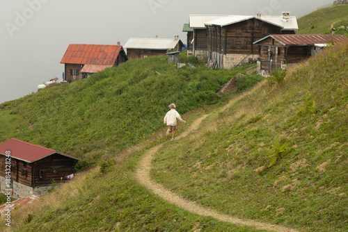 A little girl runs in the mountains against the backdrop of a village