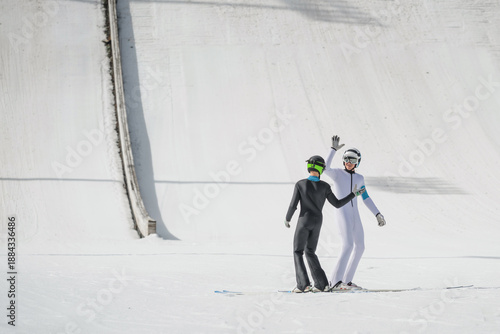 Fotografie Athletes giving high five at the bottom of ski jump training hill