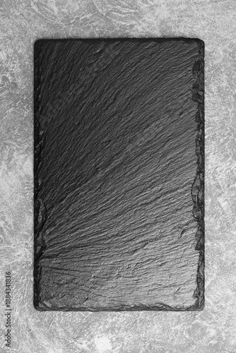 The blank slate board for restaurant food presentation. The natural black stone plate for cooked meat or fish serving.