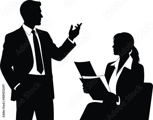 Silhouette of a formally dressed businessman gesturing while speaking to a seated businesswoman reviewing documents during a meeting