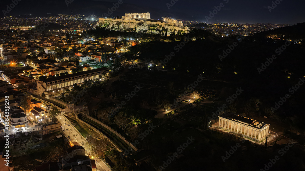 Obraz premium Aerial drone night shot of amazing illuminated ancient market of Athens or Agora featuring temple of Hephaestus, picturesque Plaka district and Acropolis hill, Attica, Greece