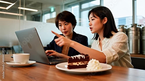 Two women working on laptop with cake