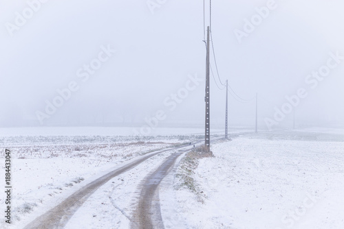 Harsh winter weather conditions in the countryside near Ninove in East Flanders, Belgium with snow and fog on a bleak landscape of agricultural fields. Winter weather in Flanders concept.