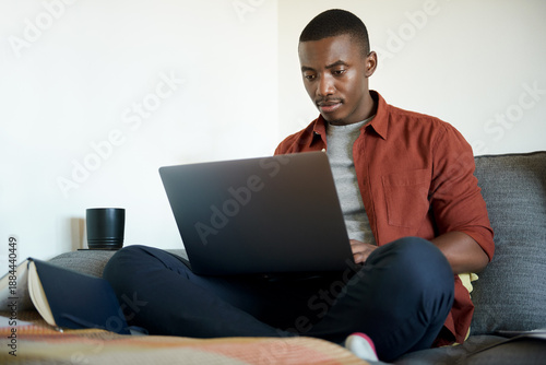 Young African man working online from home using a laptop