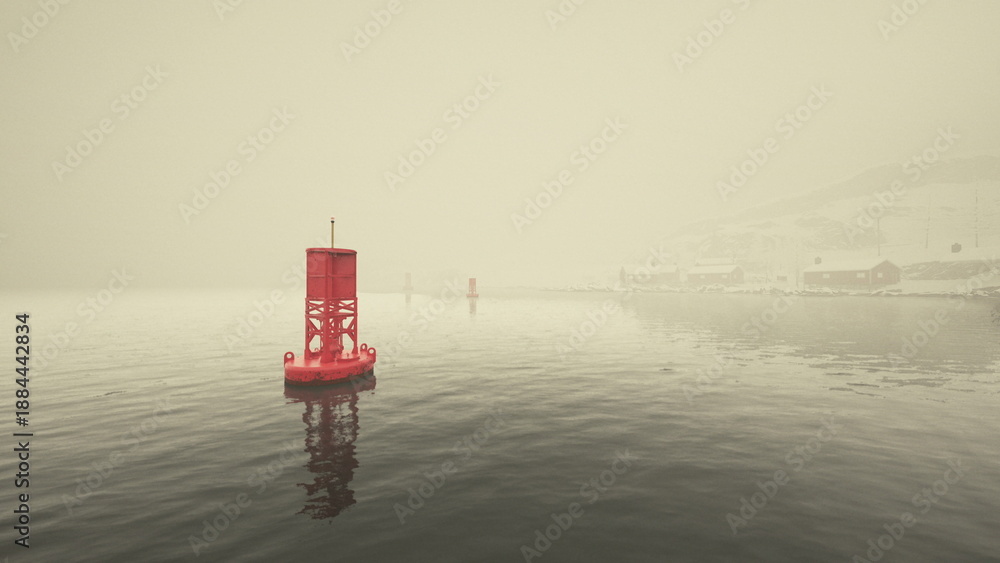 Fototapeta premium red buoy near foggy harbor and visible coastline, yellow morning haze, reflective ripples, distant buildings and pier, atmospheric serenity