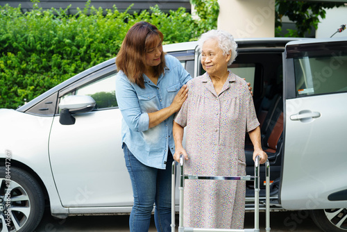 Caregiver help Asian elderly woman disability patient use walker to get in car.