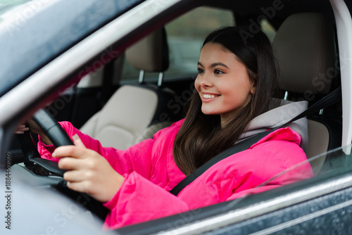 Slika na platnu Happy woman in a car, steering wheel in hands, driving safely and smiling