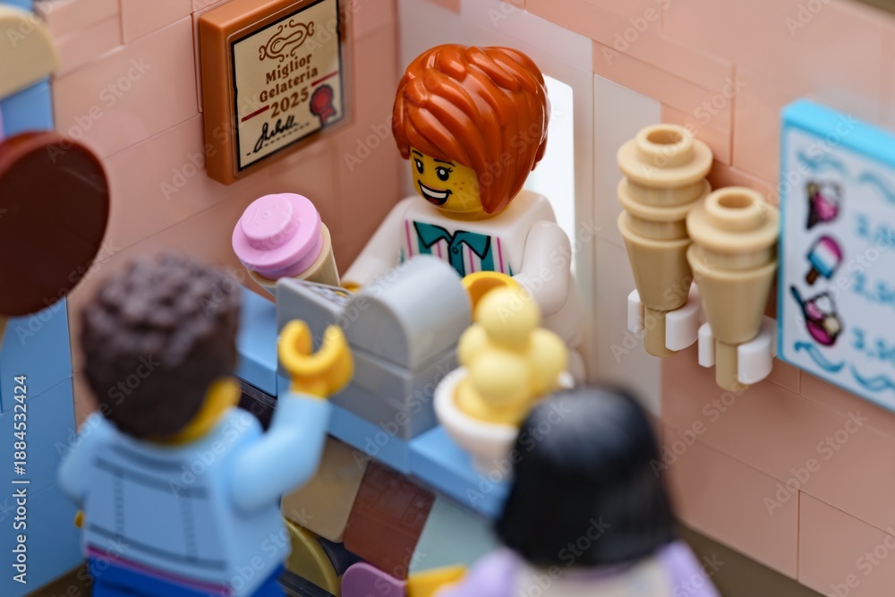 Fototapeta premium Tambov, Russian Federation - January 19, 2026 A happy Lego woman minifigure serving customers ice cream in a small italian gelateria.